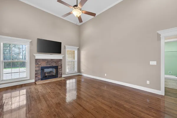 a view of a livingroom with a fireplace a ceiling fan and wooden floor