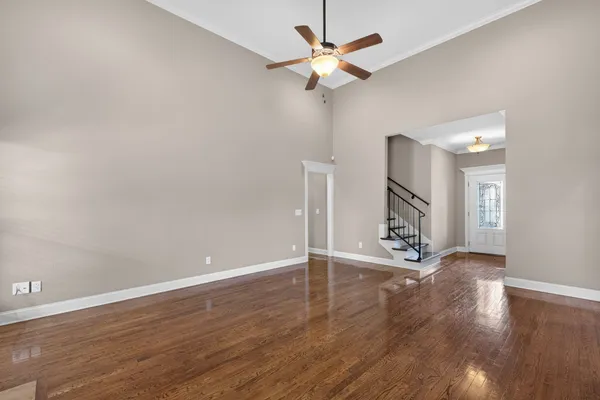an empty room with wooden floor and a ceiling fan