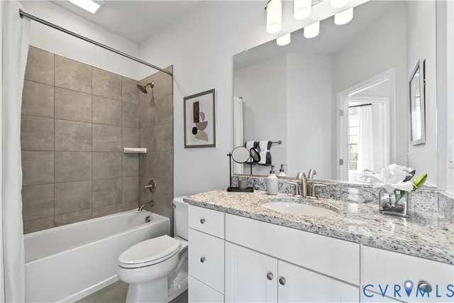 a bathroom with a granite countertop sink a toilet a mirror a bathtub and shower