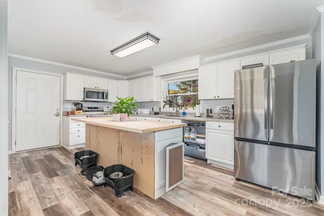 a kitchen with kitchen island a refrigerator stove and white cabinets