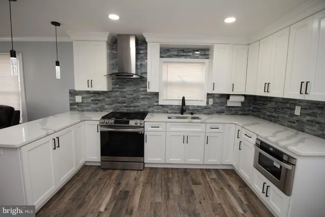 a large kitchen with a large counter top a sink stainless steel appliances and cabinets