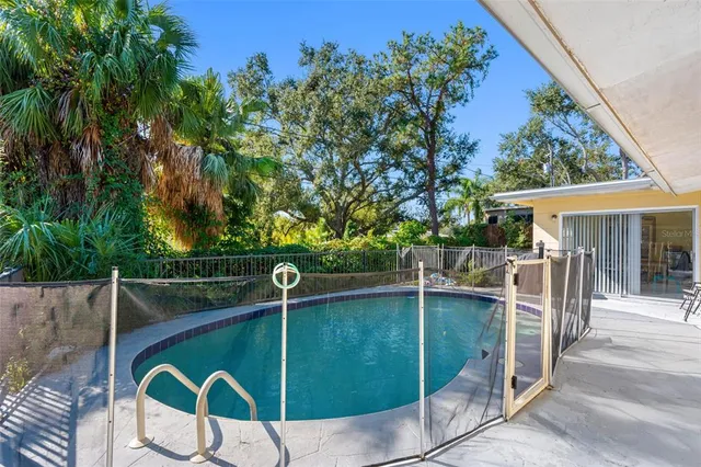 a backyard of a house with table and chairs potted plants and large tree
