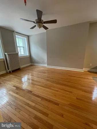 an empty room with wooden floor fan and windows