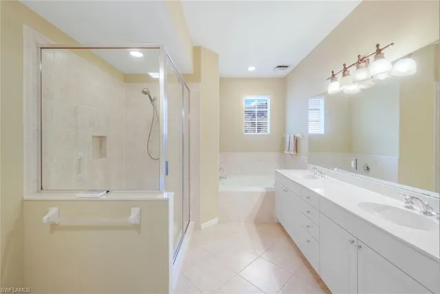 a bathroom with a double vanity sink a mirror and a bathtub
