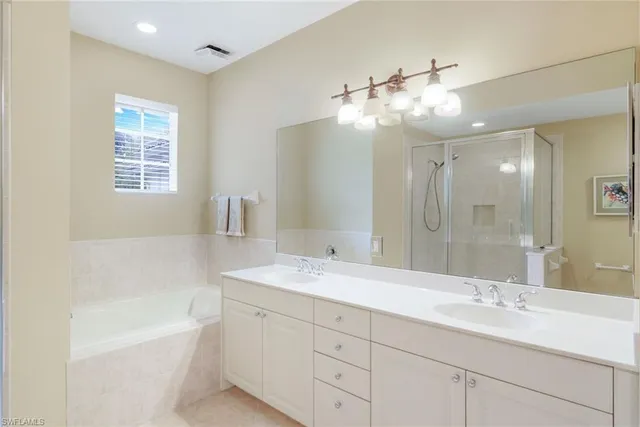 a bathroom with a sink double vanity granite tub and a mirror
