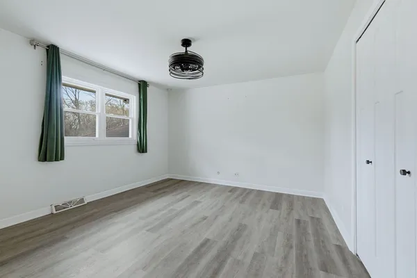 a view of an empty room with a window and wooden floor