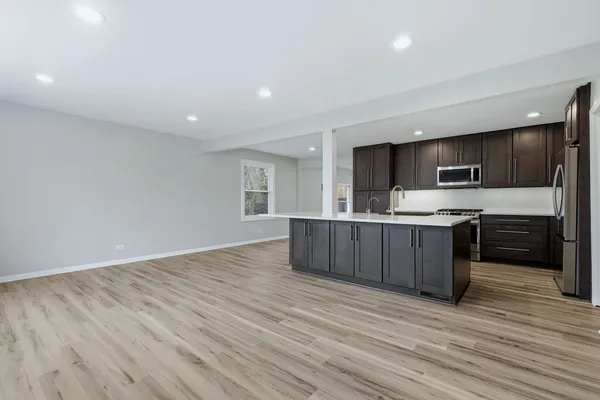 a large kitchen with stainless steel appliances granite countertop a stove a sink and a microwave