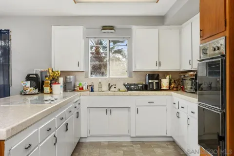 a kitchen with stainless steel appliances granite countertop a sink window and cabinets