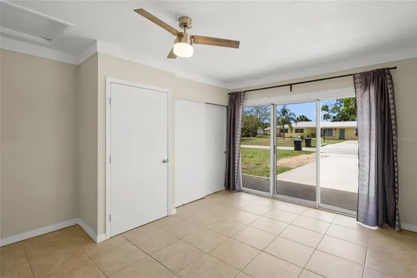 an empty room with chandelier fan and windows