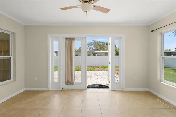 a view of a refrigerator in kitchen and empty room with windows