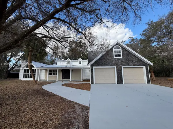 a front view of a house with a yard and large tree