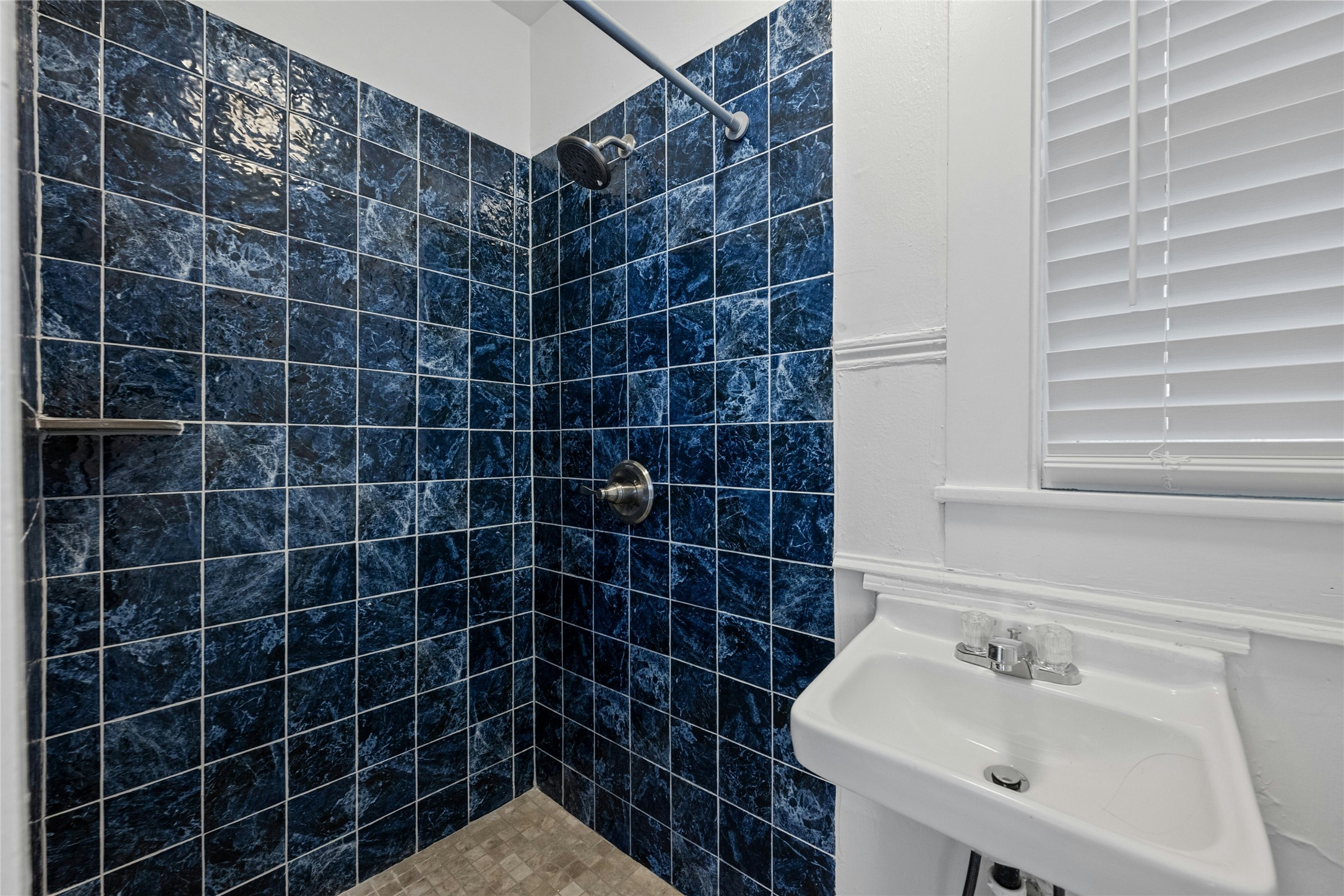 2201 Leon Street, Unit G Austin, TX 78705 - Photo 11 of 17 Shower enclosure with blue-toned tile, stainless steel shower fixtures, and a corner shelf