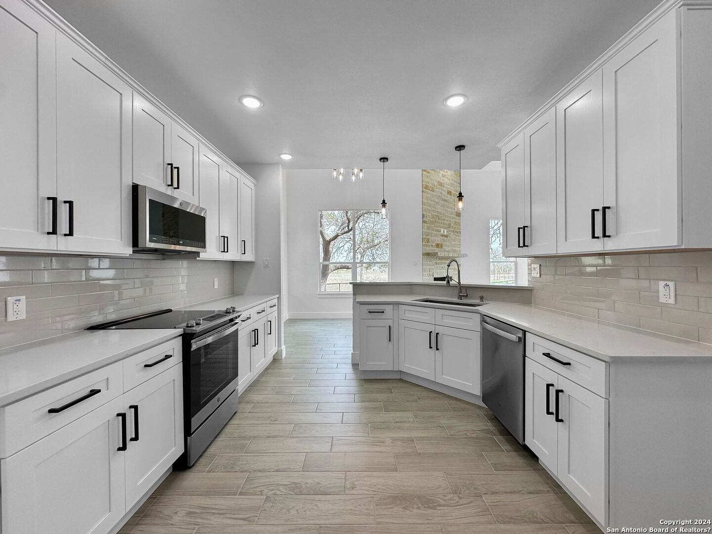 142 North Lon Price Blanco, TX 78606 - Photo 4 of 14 a large kitchen with stainless steel appliances granite countertop a stove top oven a sink dishwasher and a microwave oven on the wooden floor