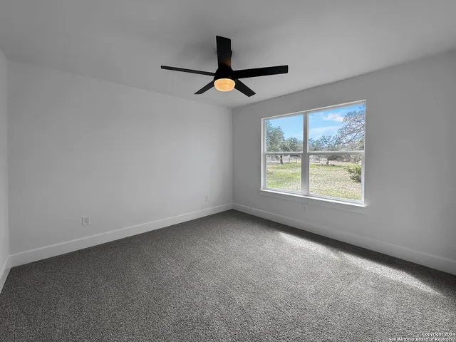 an empty room with windows and ceiling fan