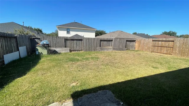 a view of a house with backyard and wooden fence