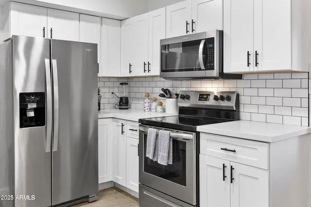 a kitchen with stainless steel appliances granite countertop white cabinets a refrigerator and a stove