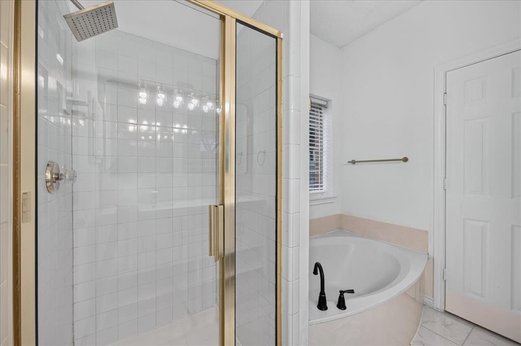 11413 Canoe Road Frisco, TX 75035 - Photo 13 of 25 Glass-enclosed shower with a brushed nickel showerhead, corner soaking tub with matte black fixtures, and white tile flooring