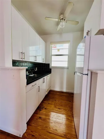 a kitchen with granite countertop white cabinets and white appliances
