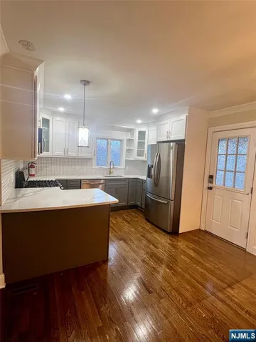 a kitchen with stainless steel appliances granite countertop a sink dishwasher a stove a refrigerator a microwave oven with cabinets and wooden floor