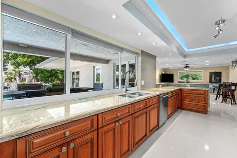 a large kitchen with stainless steel appliances granite countertop a large counter top a sink and a large window
