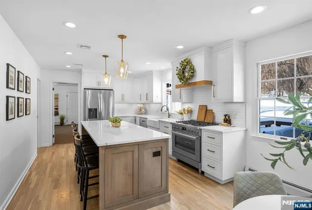 a kitchen with stainless steel appliances a sink a stove a refrigerator cabinets and living room view