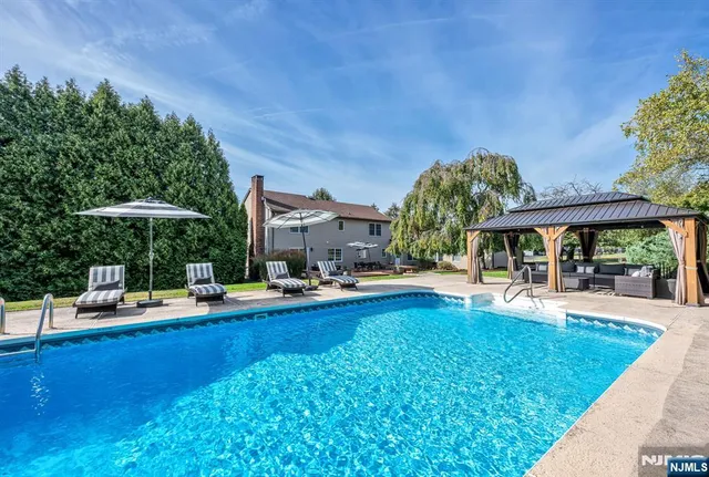 a backyard of a house with table and chairs under an umbrella