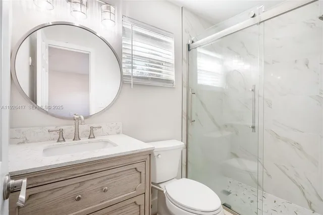 a bathroom with a sink a mirror a toilet and shower