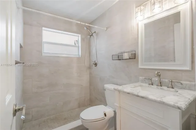 a bathroom with a granite countertop sink toilet and shower