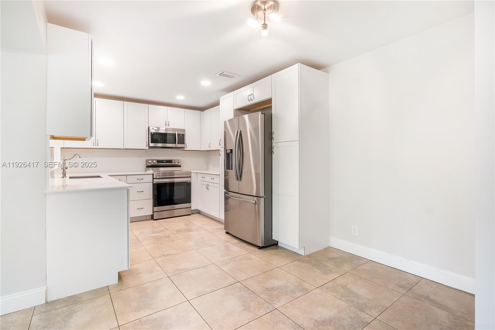 8172 Northwest 67th Avenue Tamarac, FL 33321 - Photo 4 of 44 a kitchen with a refrigerator a stove top oven and kitchen island