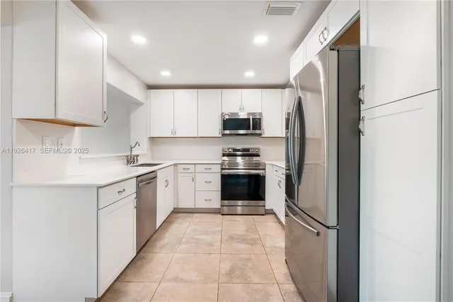 a kitchen with white cabinets and stainless steel appliances