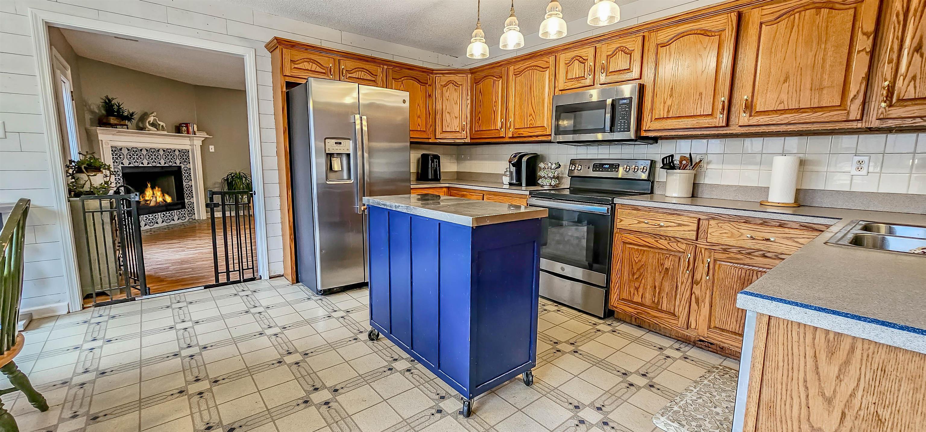 380 Bethel Road Atoka, TN 38004 - Photo 13 of 36 Kitchen with hanging light fixtures, a kitchen island, stainless steel appliances, a fireplace, and backsplash