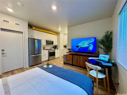 a living room with stainless steel appliances kitchen island furniture and a flat screen tv