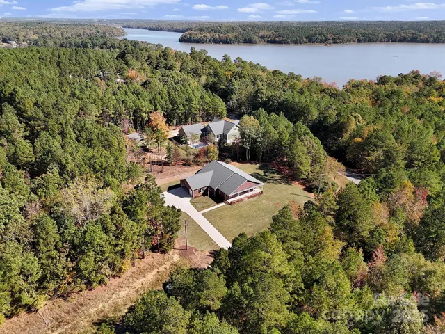 an aerial view of a residential houses with outdoor space and trees