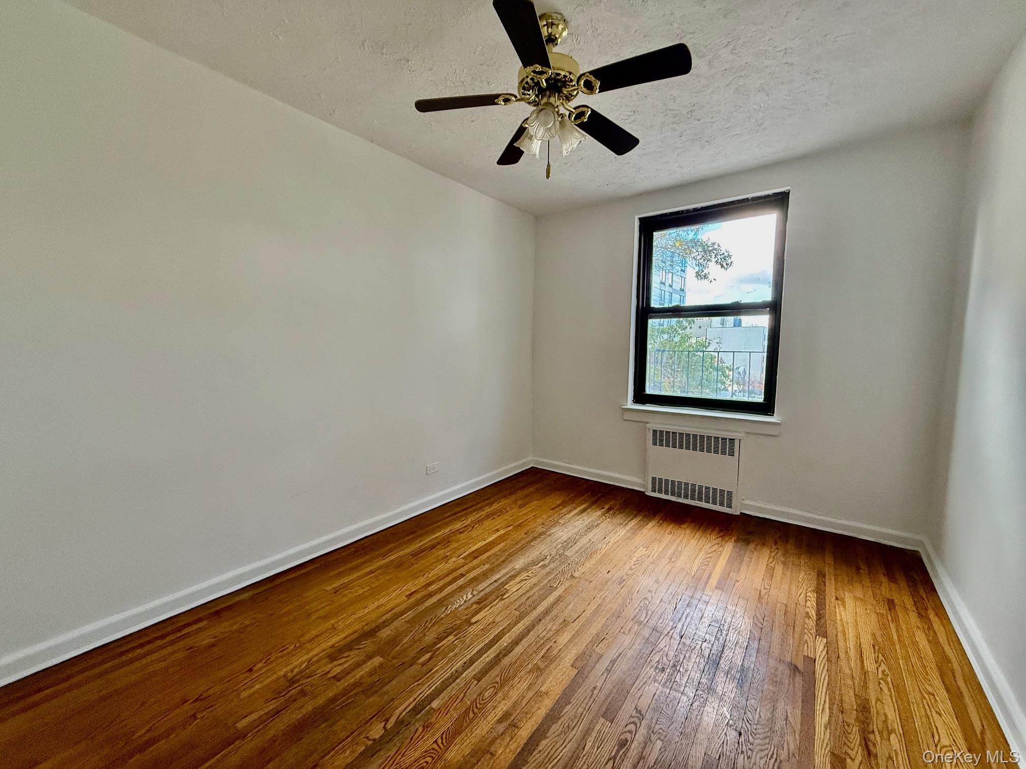 112-24 Northern Boulevard, Unit 3G Queens, NY 11368 - Photo 15 of 33 Second bedroom with hardwood / wood-style floors, radiator heating unit, a textured ceiling, and ceiling fan