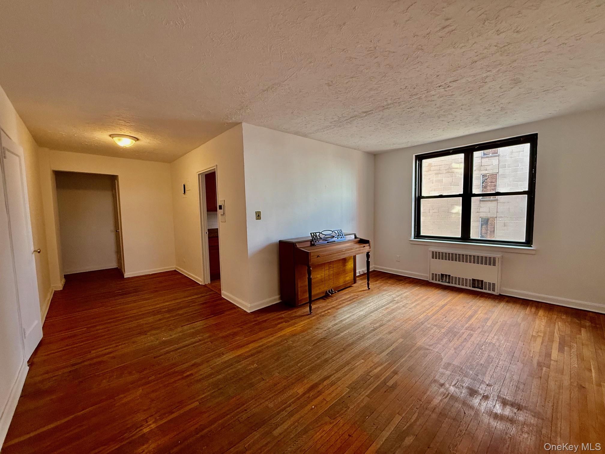 112-24 Northern Boulevard, Unit 3G Queens, NY 11368 - Photo 8 of 33 Living room with a textured ceiling, hardwood / wood-style floors, and radiator