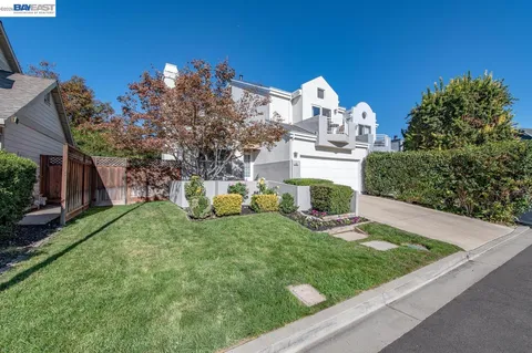 a view of a house with a yard and a large tree