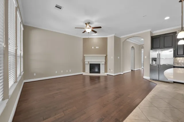 a living room with stainless steel appliances kitchen island a fireplace and wooden floor
