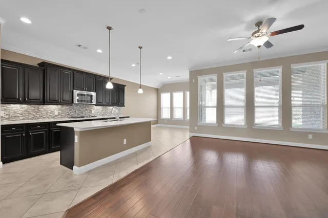 a large kitchen with stainless steel appliances granite countertop a stove a sink dishwasher a refrigerator and a wooden floor