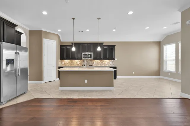 a view of kitchen with kitchen island a sink wooden floor and a refrigerator