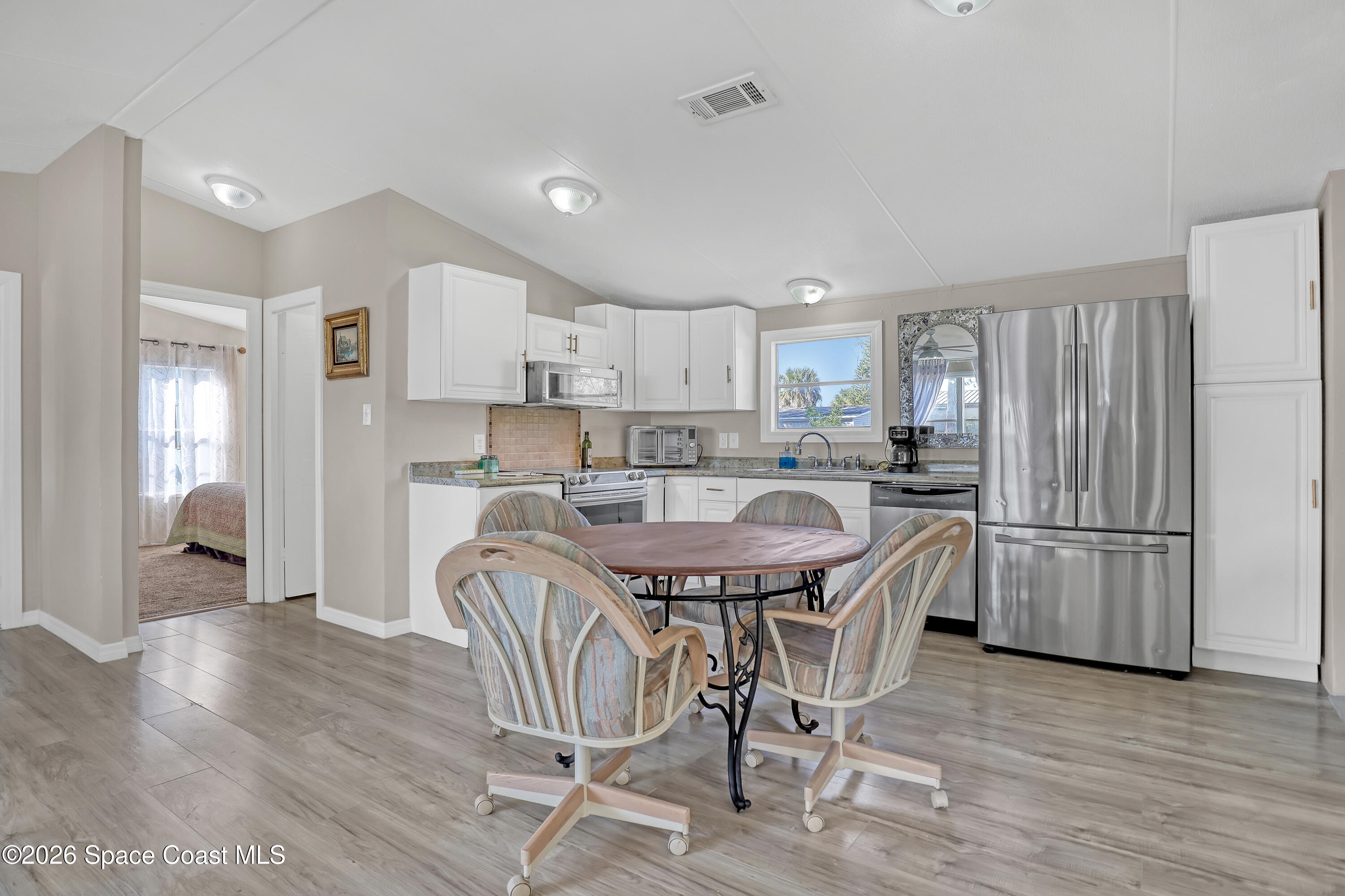 a kitchen with stainless steel appliances a refrigerator a stove a sink dishwasher and a dining table with wooden floor