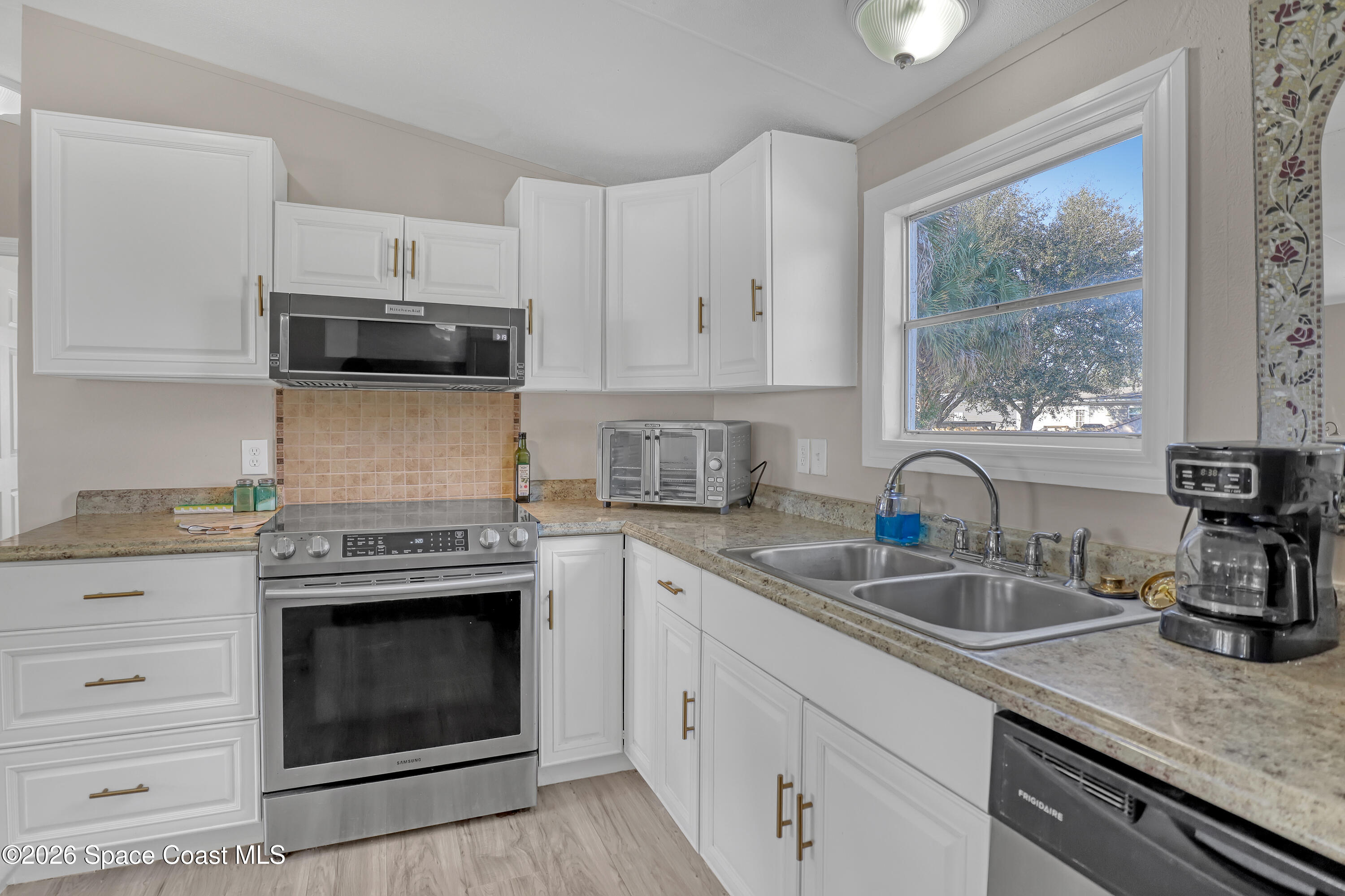 354 Akorn Street Cocoa, FL 32927 - Photo 4 of 29 a kitchen with granite countertop a sink stainless steel appliances and cabinets