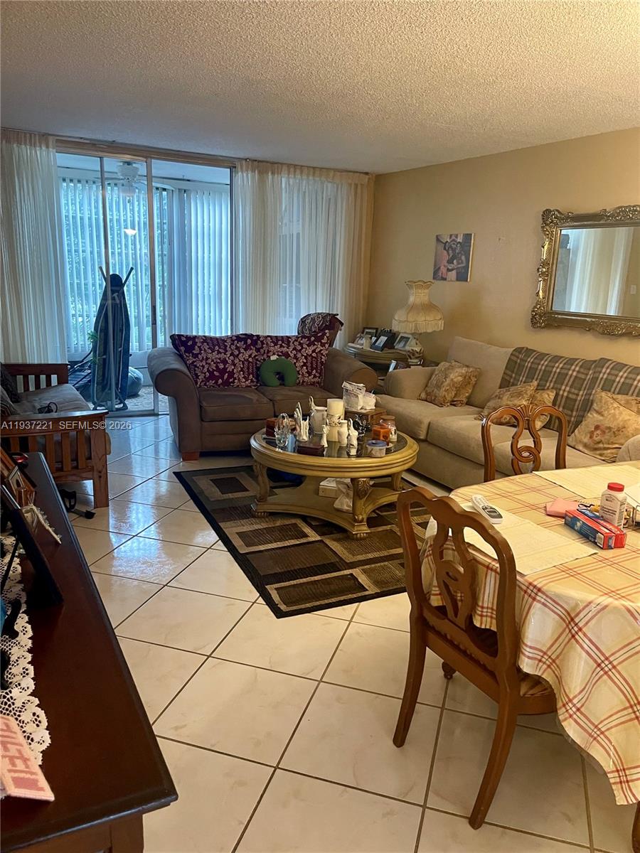 8351 Sands Point Boulevard, Unit A208 Tamarac, FL 33321 - Photo 11 of 15 a living room with furniture a fireplace and a large window