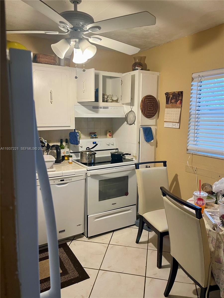 8351 Sands Point Boulevard, Unit A208 Tamarac, FL 33321 - Photo 5 of 15 a kitchen with a stove cabinets and chairs