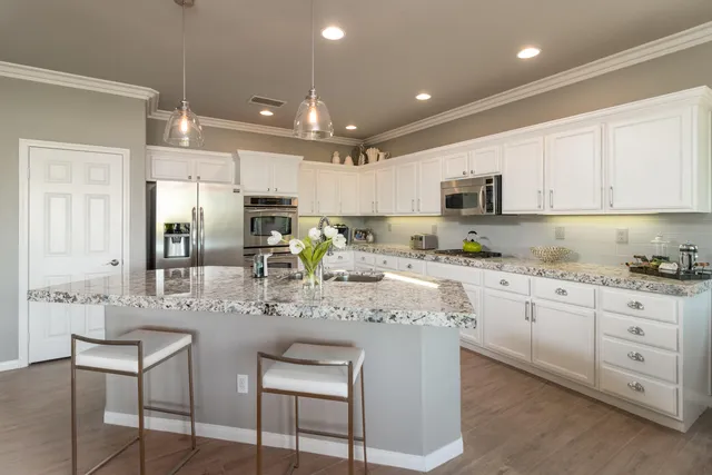 a kitchen with kitchen island granite countertop a sink cabinets and stainless steel appliances