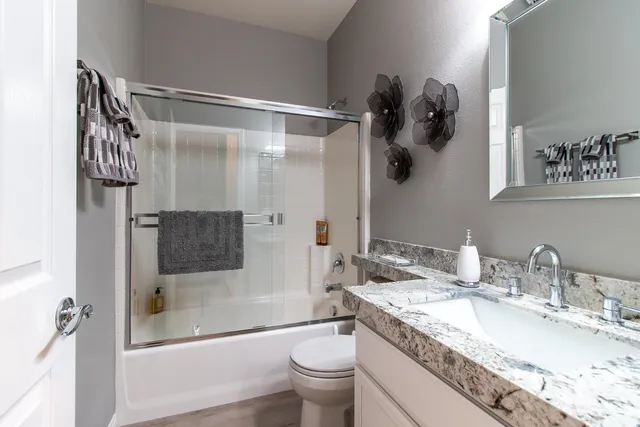 a bathroom with a granite countertop sink a toilet and shower