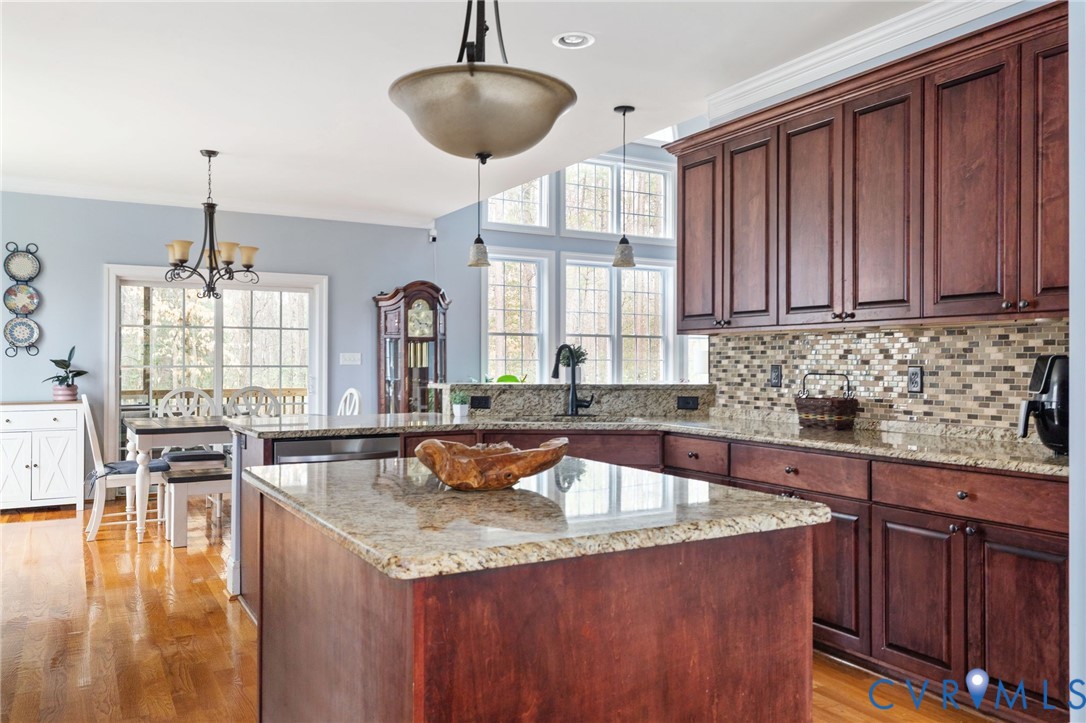 8825 First Branch Lane Chesterfield, VA 23838 - Photo 11 of 63 a kitchen with granite countertop a stove a sink a dining table and chairs with wooden floor