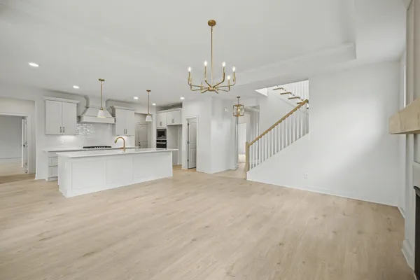 a view of large kitchen with granite countertop a stove a sink a refrigerator and white cabinets with wooden floor