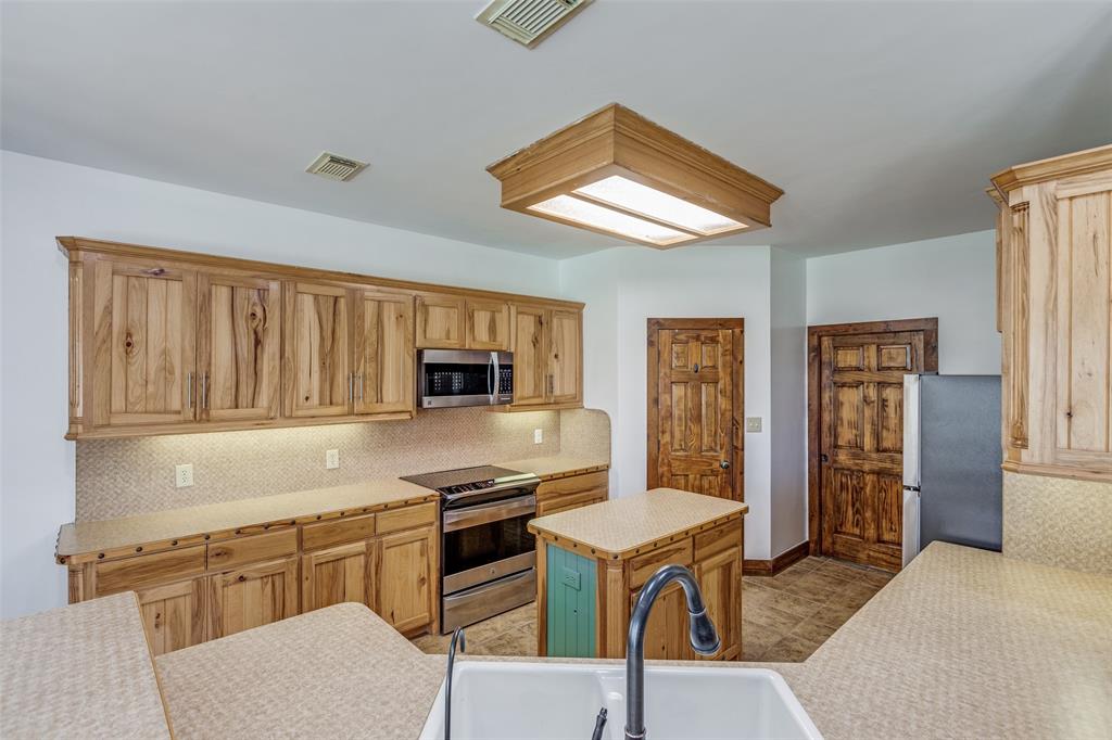 11744 Foutch Road Pilot Point, TX 76258 - Photo 16 of 35 a kitchen with stainless steel appliances granite countertop a stove top oven a sink dishwasher and a refrigerator with wooden floor
