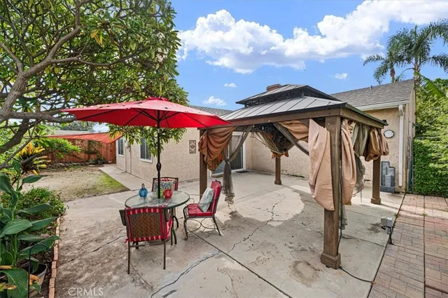 a backyard of a house with table and chairs under an umbrella