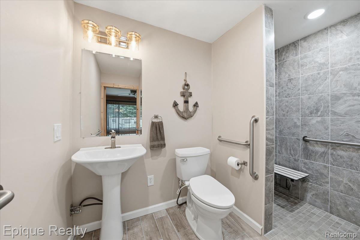 1221 Rhodes Road Lake Orion, MI 48360 - Photo 26 of 72 Pedestal sink with brushed nickel faucet, wall-mounted mirror, and overhead vanity lighting